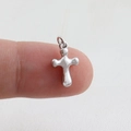 Macro shot of a polished silver cross pendant with rounded edges held on a fingertip - Silver Polished (06)