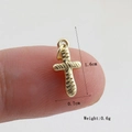 Detailed macro view of a small golden cross pendant showing 1.6cm x 0.7cm dimensions - Gold Etched (15)