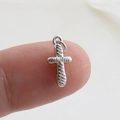 Macro shot of a small silver cross charm with spiral texture held on a fingertip - Silver Spiral (16)