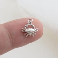 Macro view of a small silver crab charm pendant resting on a fingertip for size reference - Silver Mini Crab Style(10)