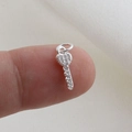 Macro detail of a tiny silver key pendant with pavé cubic zirconia on a fingertip - Silver Key Style (12)