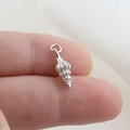 Macro view of a tiny silver seashell pendant held on a fingertip for size scale - Silver Spiral Conch Style(16)