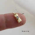 Detailed view of a gold bow pendant with white zircon being held to show small scale - Gold Bow Style (19)