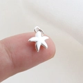 Close-up of a tiny polished silver starfish pendant accessory on a fingertip - Silver Starfish Style(20)