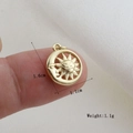 Macro view of a 1.6cm gold celestial sun and moon pendant held on a fingertip - Gold Anthropomorphic Sun Moon Disc Style (03)