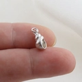 Macro view of a tiny silver conch seashell pendant for DIY jewelry on a fingertip - Silver Textured Conch Style(24)