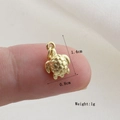 Macro shot of a golden turtle pendant charm with textured shell detail on a finger - Gold Turtle Style(25)