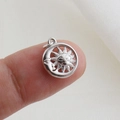 Macro shot showing the scale of a sun and moon engraved silver celestial charm on a fingertip - Silver Sun Moon Embossed Face Style (04)