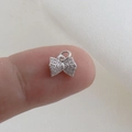 Macro detail of a mini bow charm with pavé zircon setting shown on a fingertip - Silver Pave Bow Style (24)