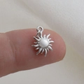 Dettaglio del ciondolo a sole in argento sul dito per mostrare le dimensioni ridotte - Stile Fiamma di Fuoco Totem Solare Argento (8)