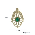Detailed view of a gold Hamsa hand pendant with sparkling zircons and a green center stone - Pave Zircon Green Emerald Hamsa (04)