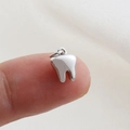 Close-up of a polished tooth-shaped silver charm on a fingertip for size reference - Silver Mini Tooth Style(30)