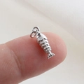 Macro shot of a fish-shaped silver metal pendant with fine scales on a white fabric background - Silver Fish Style(32)