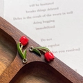 Macro detail of tulip flower charms with red and green enamel on walnut wood tray - Red Gold Ring