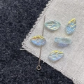 Macro shot of iridescent leaf-shaped glass beads with colorful AB coating and vein textures - Blue Green Leaf