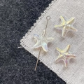 Macro shot of iridescent starfish glass beads on silver pins for DIY jewelry making - White Starfish
