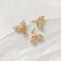 Macro shot of three gold fishtail pendants with clear zircons on a white ceramic plate - Hollow Fish Tail / Gold