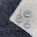 Iridescent ammonite glass beads for DIY jewelry with silver pin on a textured background - Light Blue Conch