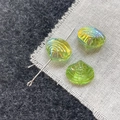 Close-up of iridescent green shell glass beads showing the hole and DIY assembly - Green Shell
