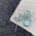 Macro shot of colorful shell-shaped glass beads with iridescent aurora finish and pins - Blue Shell