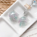 Detailed macro view of an iridescent resin jellyfish pendant with glitter finish and bead chain - Pink Blue Green Gradient