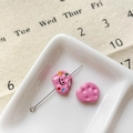 Perle nuage rose avec sourire et épingle métallique sur plateau en céramique blanc - Biscuit Souriant Rose Rouge
