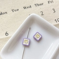 Détail macro de perles carrées violettes en forme de cœur pour bijoux sur plateau blanc - Cœur Carré Violet