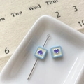 Macro shot of blue square alloy beads with purple heart design and a silver pin on a plate - Blue Square Heart