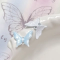 Dettaglio macro di ciondoli a farfalla blu e bianchi con anellini per gioielli DIY - Farfalla Blu Bordo Bianco