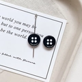 Detailed macro view of black four-hole button style earrings on a minimalist white card - Round Shape - Black