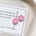 Detailed view of pink button-shaped charm with white dots on an elegant beige tray - Round Shape - Rose Pink