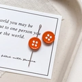 Close-up of bright orange button-shaped stud earrings with four-hole design on tray - Round Shape - Orange