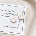Close-up of creative button-shaped earrings in cream with pink dots on a paper background - Round Shape - White