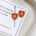 Detailed view of orange heart-shaped four-hole buttons with a silver metal pin for DIY jewelry - Heart Shape - Orange