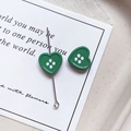 Close-up of green heart-shaped resin buttons with four holes on a silver metal pin - Heart Shape - Dark Green