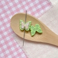Macro detail of two butterfly-shaped resin DIY sewing notions with a metal pin and star pattern - Green Brown Double Layer Butterfly