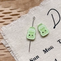 Vue macro de breloques émaillées vertes Happy pour bijoux DIY et chaînes de téléphone - Bouteille de Lait Verte