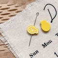 Détail macro d'épingle poisson émail jaune avec longue aiguille sur tissu texturé - Poisson Séché Jaune
