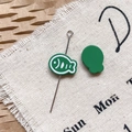 Macro shot of green fish-shaped DIY jewelry charms on textured linen and kraft paper background - Dark Green Dried Fish