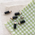 Macro detail of pencil-shaped alloy beads for DIY jewelry on textured fabric - Black