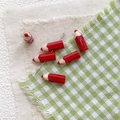 Macro shot of 3D red pencil alloy beads with threading holes for DIY bracelet crafting - Red