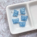 Vue macro de perles papillon en verre tchèque bleu clair nacré pour création de bijoux DIY - Bleu avec Tracé Bleu Iridescent