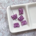 Gros plan de perles papillon en verre violet avec détails gravés aux bords dorés - Violet Blanc