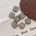 Macro detail of square amber glass beads with light blue floral engraving for DIY jewelry - 20#