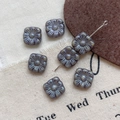 Macro view of six square floral glass beads with embossed petals and metallic luster - 2#