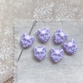 Detailed view of six marbled purple cat head beads on a rustic linen background - White Purple