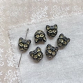 Macro shot of 6pcs black and gold vintage cat-head glass beads on linen fabric - Black Gold