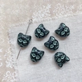 Detailed view of vintage black cat head beads with green patina for jewelry making - Black Green