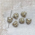 Close-up of white cat-shaped beads with gold details for DIY jewelry on linen cloth - White Gray Gold