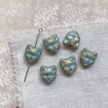 Macro view of blue and gold vintage cat head glass beads on rustic linen fabric background - Yellow Green Blue